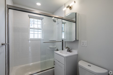 a white bathroom with a shower and a sink and a toilet