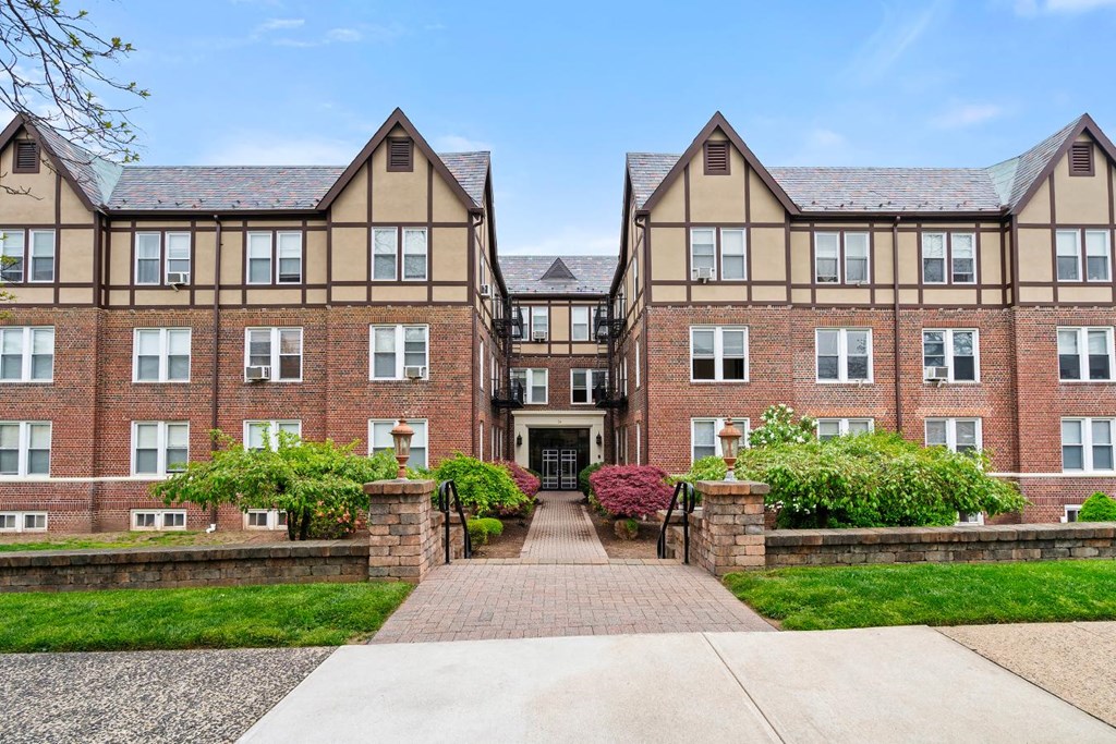 front view of an apartment building with a walkway and grass