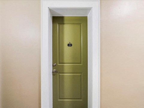 A green door with a black handle in a room.