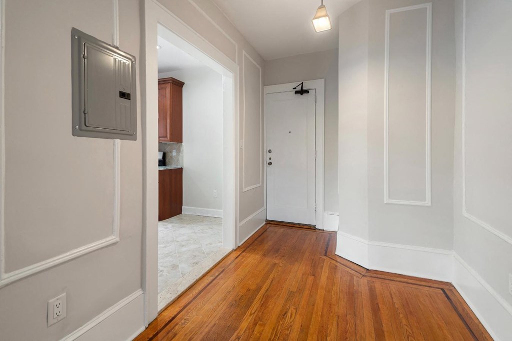 a renovated living room and hallway with wood flooring and white walls