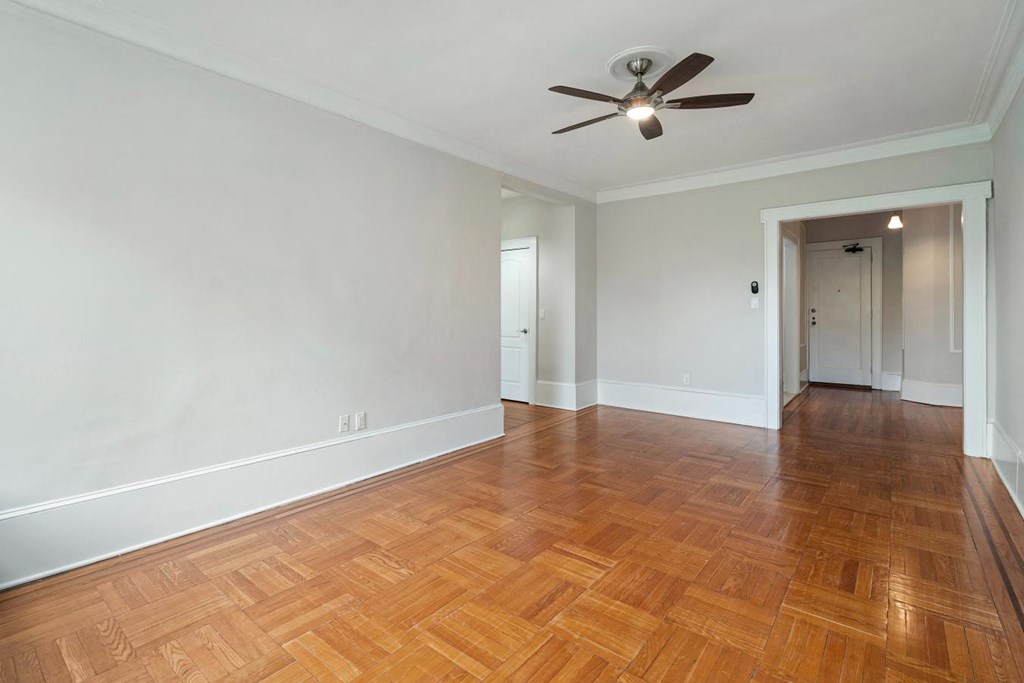 an empty living room with wood flooring and a ceiling fan