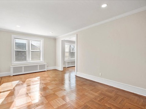 A room with wooden flooring and two windows.