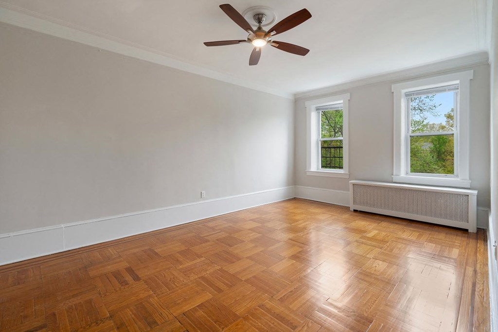 an empty living room with wood floors and a ceiling fan