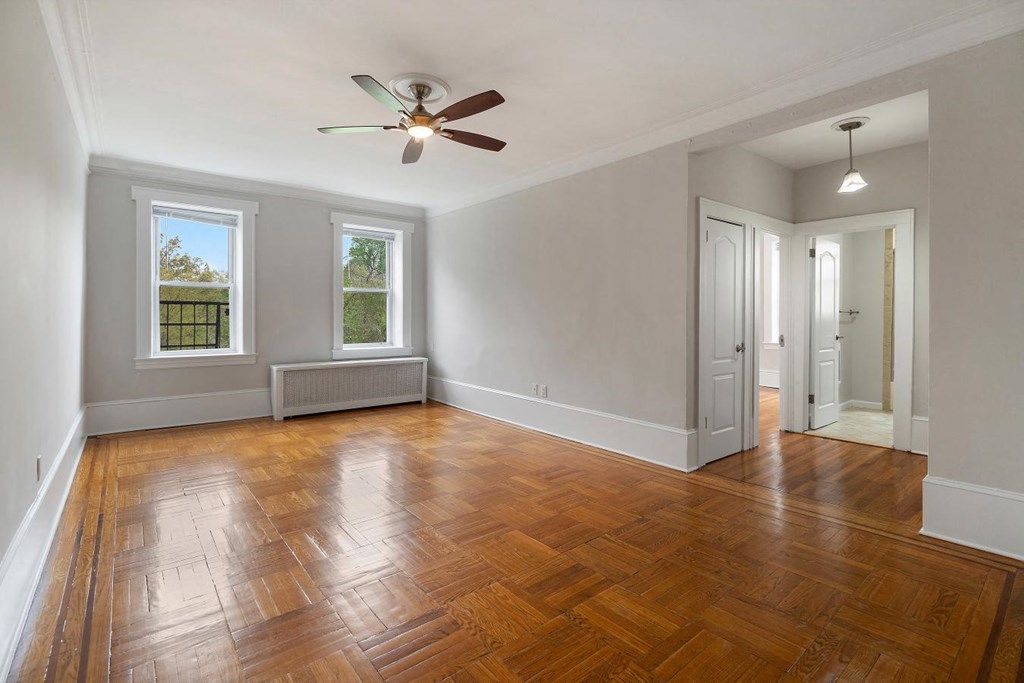 an empty living room with wood floors and a ceiling fan
