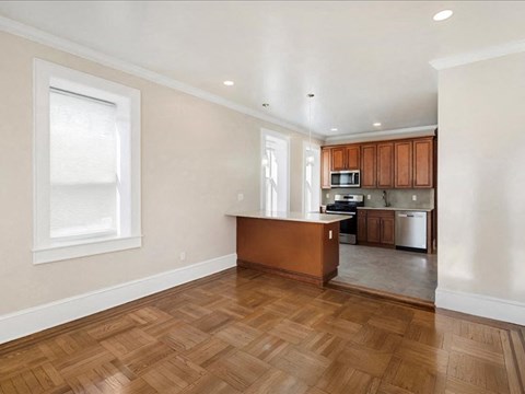 A kitchen with wooden floors and a white wall.
