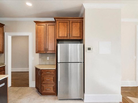A kitchen with a stainless steel refrigerator and wooden cabinets.