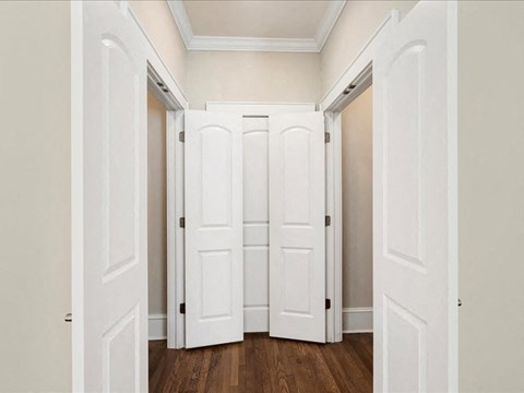 A hallway with white doors and wooden floors.