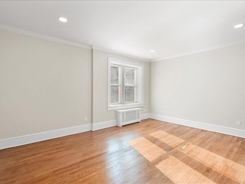 A room with a window and wooden flooring.