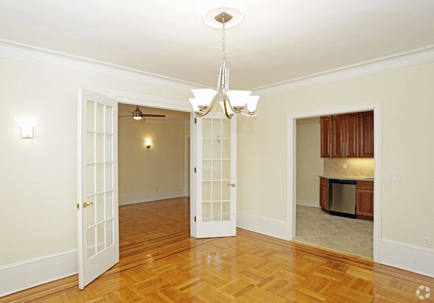 a dining room and living room with doors open to the kitchen and a wood floor