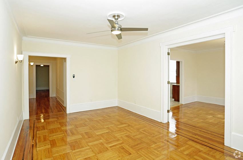 an empty living room with wood floors and a ceiling fan