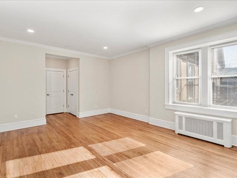 A room with wooden floors and a window with blinds.