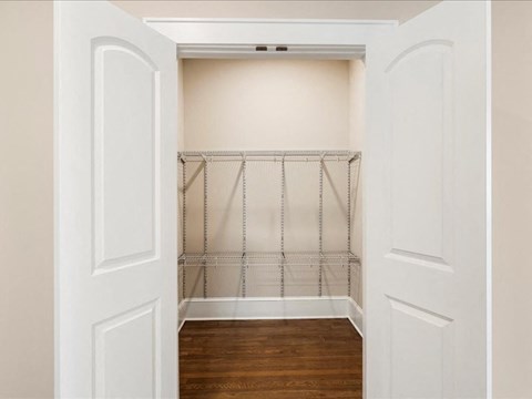 A white closet with a wire shelving unit and wooden floors.