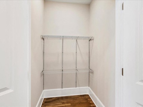 A white closet with a shelf and a door.
