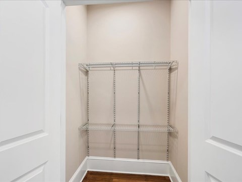 A white closet with a shelf and a white door.