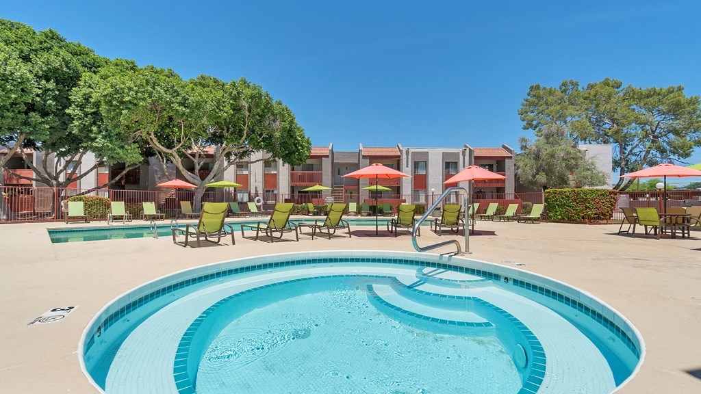 a soothing spa with a background view of swimming pool with chairs and umbrellas in front of the resident clubhouse at Spring Meadow Apartments, Arizona, 85302