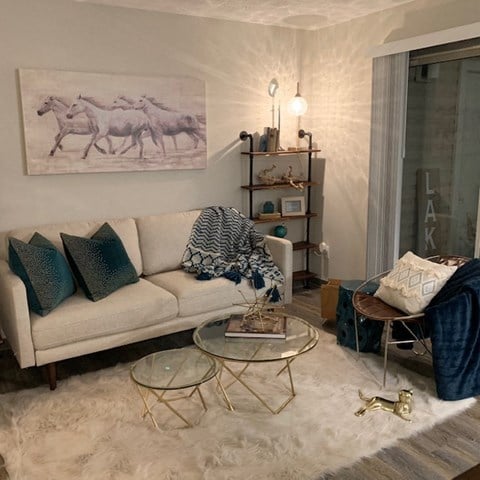 a living room with a white couch and a painting of horses