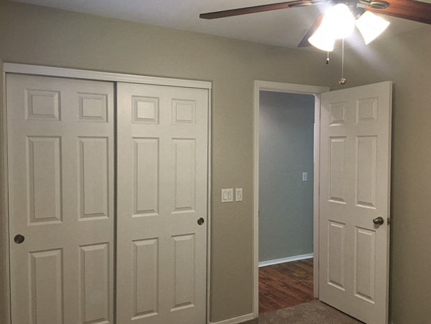 an empty room with white doors and a ceiling fan