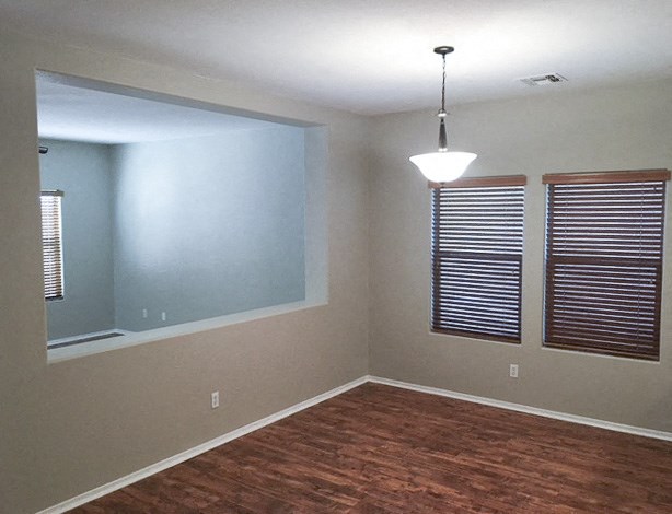 an empty living room with a hard wood floor and a mirror