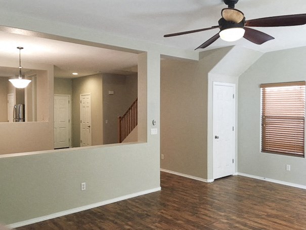 an empty living room with a ceiling fan