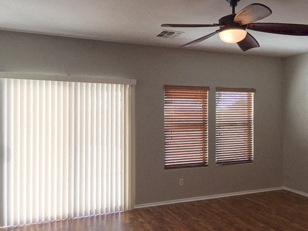 a living room with two windows and a ceiling fan