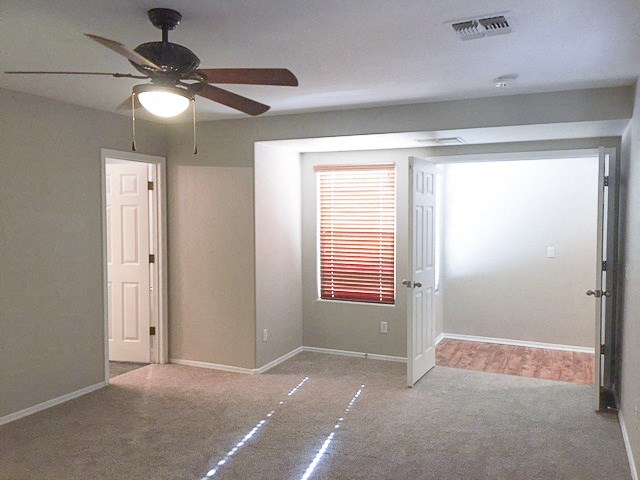 an empty room with a ceiling fan and a door