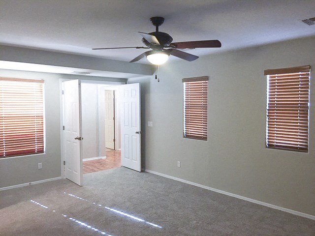 an empty living room with a ceiling fan and a door