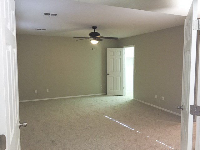 an empty living room with a ceiling fan and a door