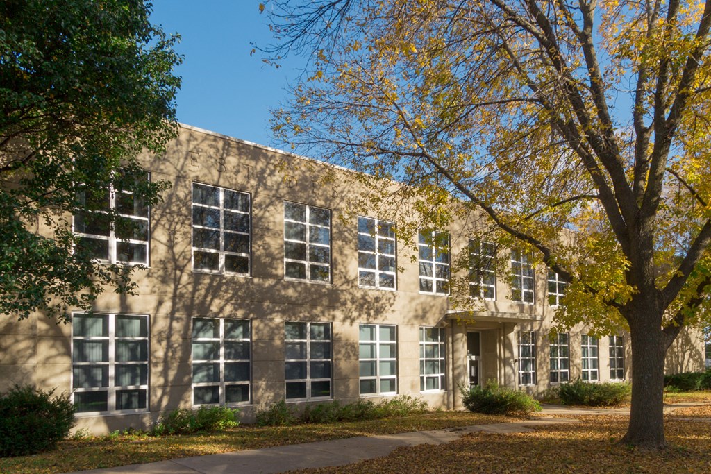 the exterior of a building with trees in front of it