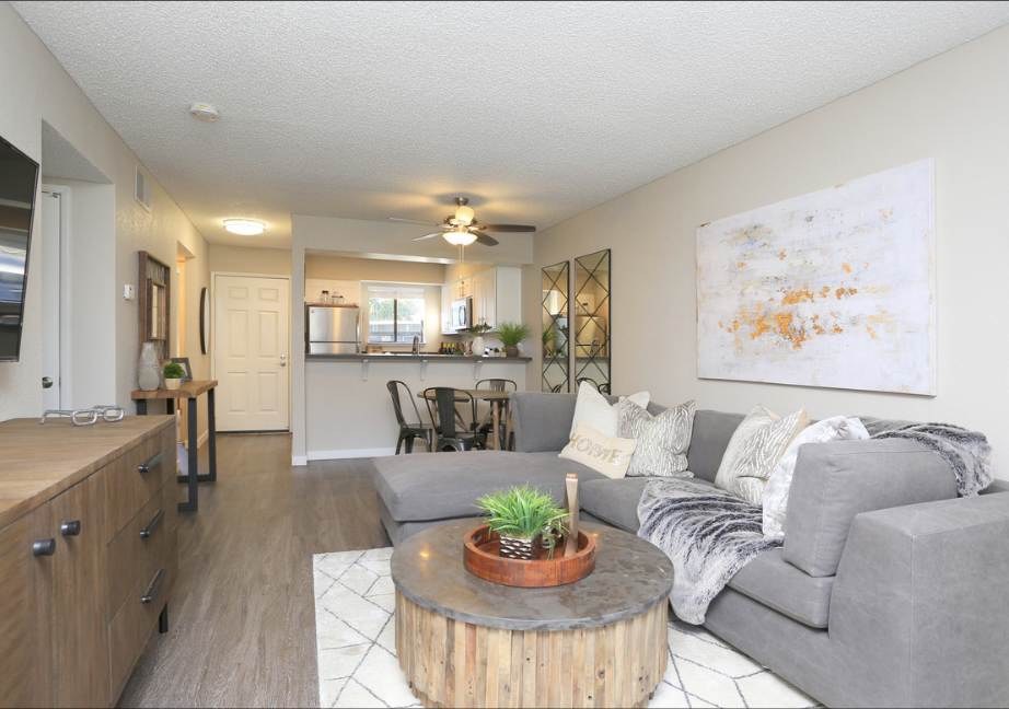 A living room with a grey couch, a wooden coffee table, and a painting on the wall.