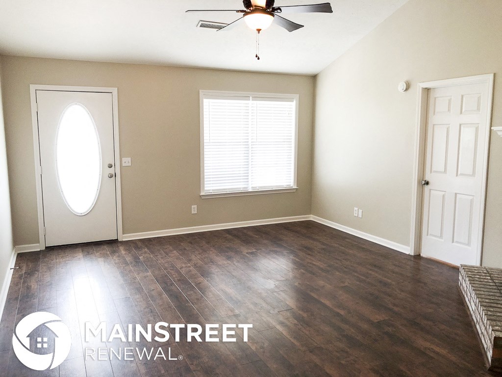 an empty living room with wood floors and a ceiling fan