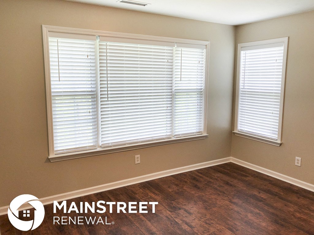 a living room with wood floors and a window with white blinds