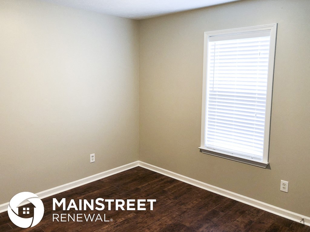 a small room with a window and wooden floors