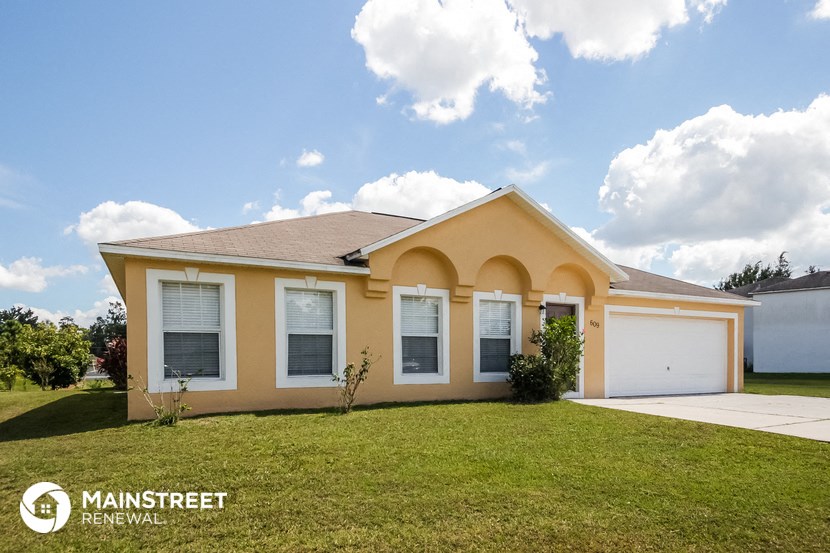 a yellow house with a lawn and a garage