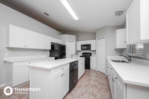 a white kitchen with black appliances and white counters