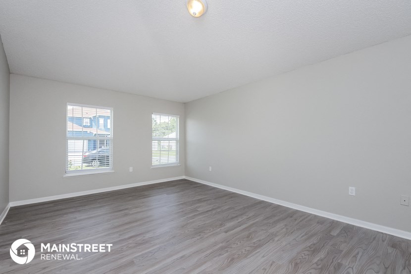 the spacious living room with wood flooring and white walls
