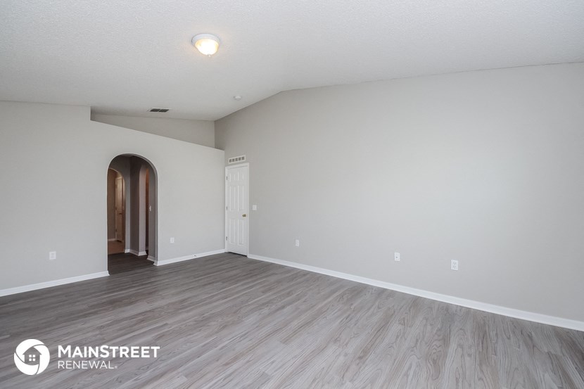 the spacious living room with wood flooring and white walls