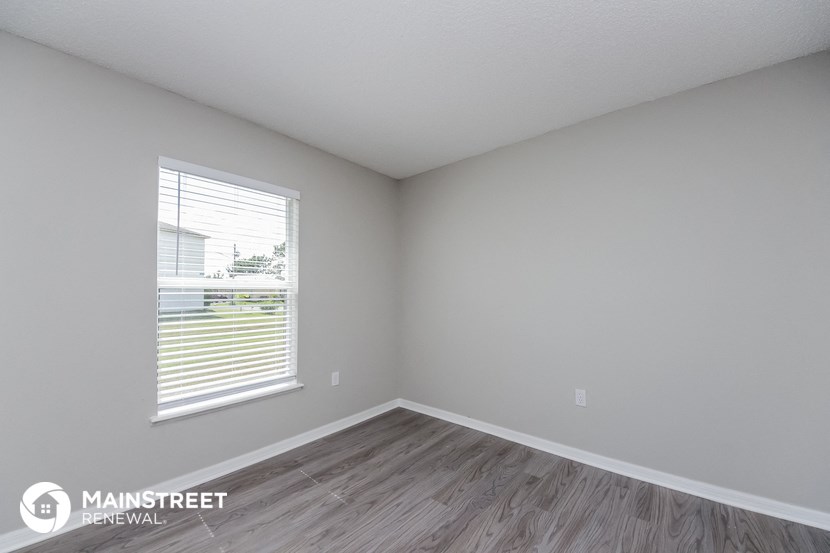 the spacious living room with wood flooring and a large window