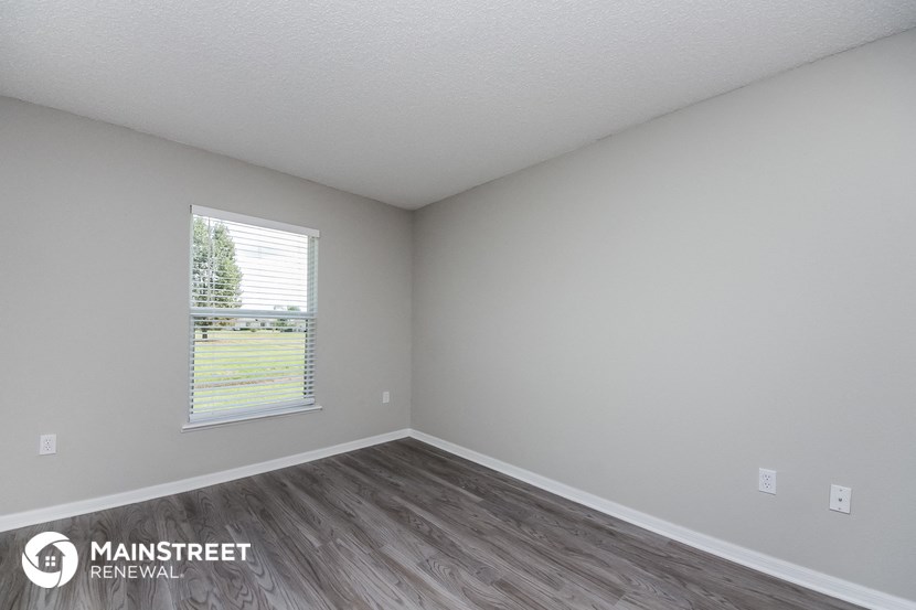 the spacious living room with wood flooring and a window
