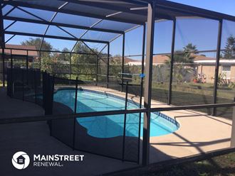 a swimming pool in a screened in pool enclosure with glass walls and a fence