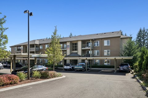 A parking lot in front of a building with cars parked.