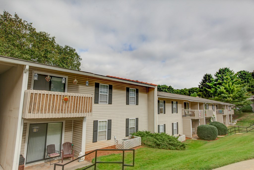 an exterior view of a white apartment building with a porch and a lawn