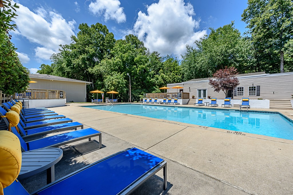 our resort style swimming pool with blue chairs and yellow umbrellas