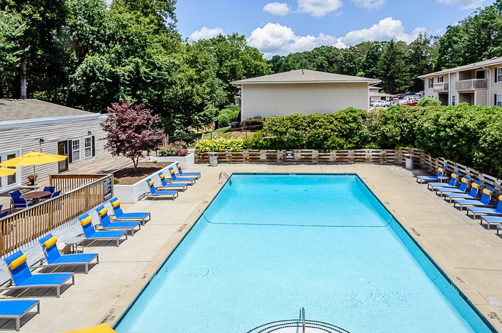 a swimming pool with blue lounge chairs next to a building