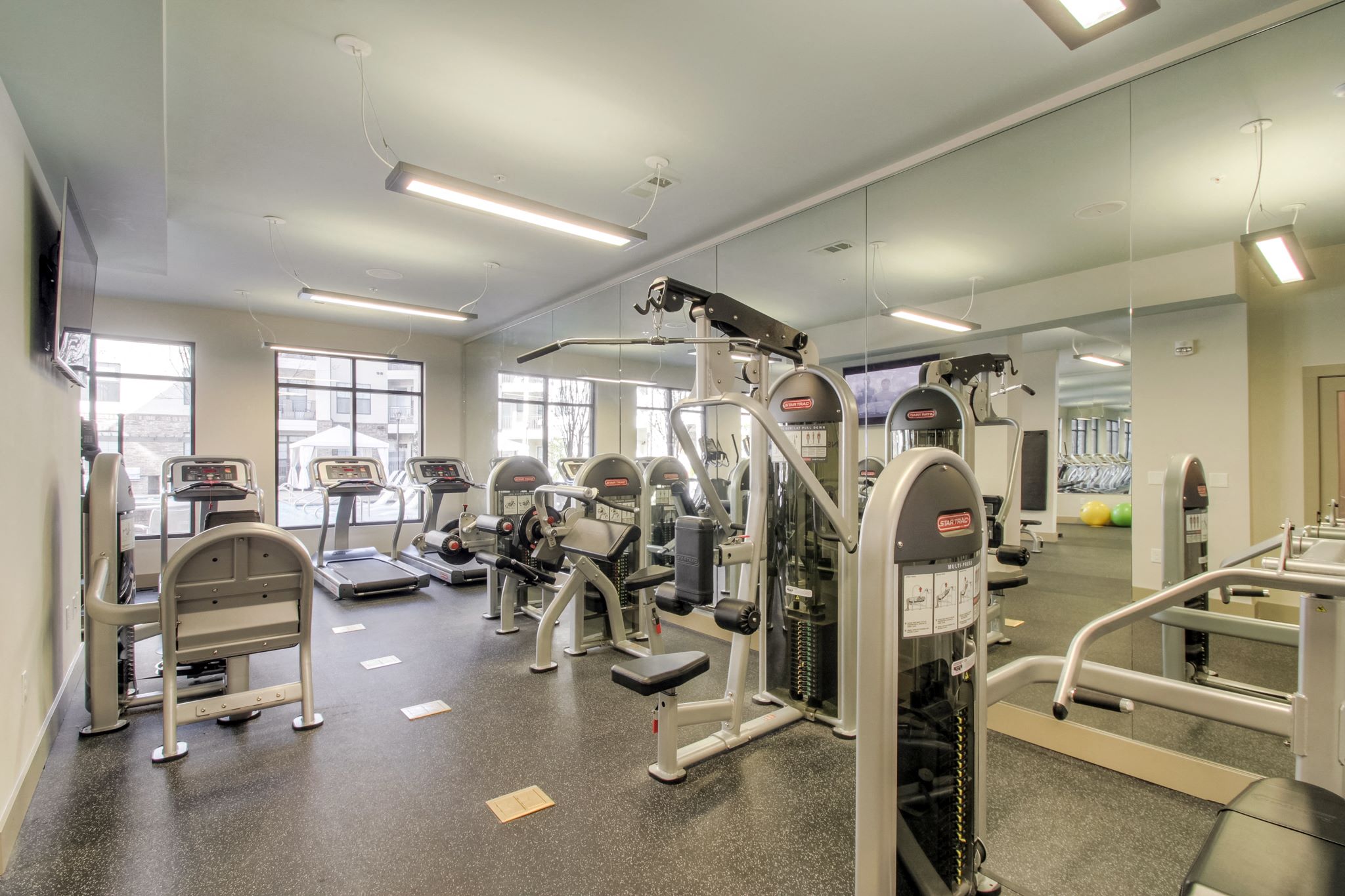 A gym with a variety of equipment including treadmills, weights, and exercise machines.