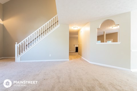 a spacious living room with a staircase and carpet flooring