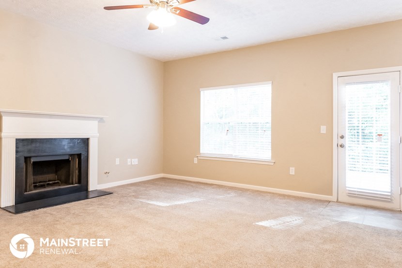 a living room with a fireplace and a ceiling fan