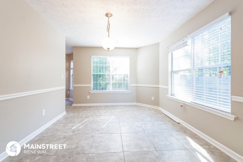 a spacious dining room with large windows and tile flooring