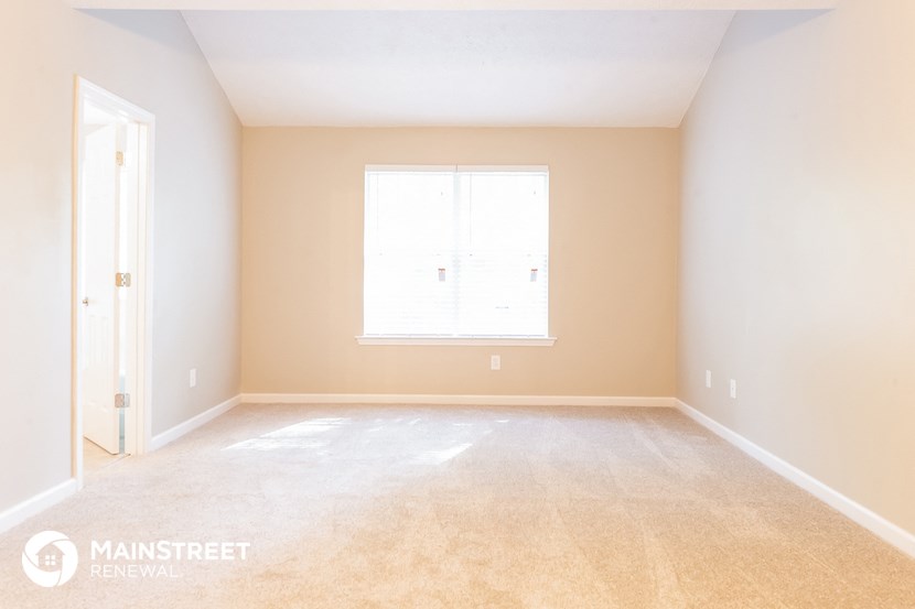 the bedroom of a home with white walls and a window