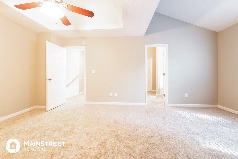 a spacious living room with carpet and a ceiling fan
