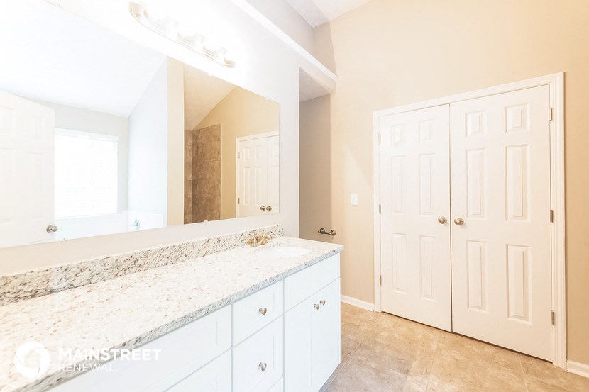a bathroom with white cabinets and a counter top and a mirror